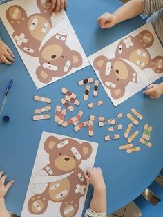 two children sitting at a table making teddy bear cut outs