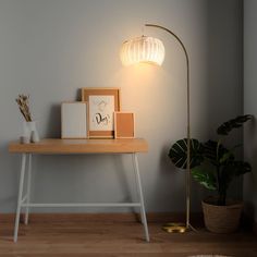 a wooden table topped with a lamp next to a potted plant and framed pictures