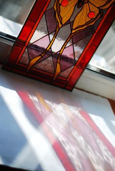 a stained glass window sitting on top of a white table next to a red and yellow flag