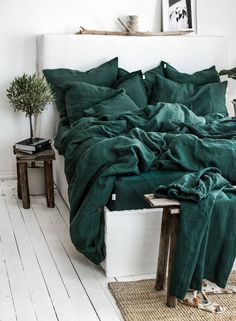 a bed covered in green sheets and pillows