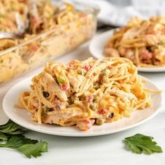 pasta with chicken and vegetables on a white plate next to another dish in the background