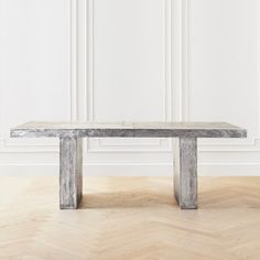 a wooden table sitting on top of a hard wood floor next to a white wall