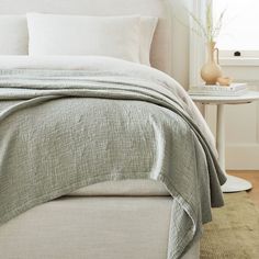 a bed with white sheets and pillows in a bedroom