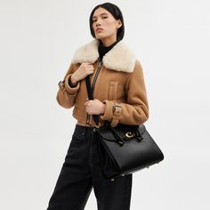 Our Broome has all the effortless cool of its namesake Soho street. The spacious foldover silhouette is crafted of luxe refined leather with a high shine finish and secures with our pushlock “C” closure. Featuring pockets inside and out for easy organization and room for a 16” laptop carry it by hand or use the detachable strap to wear it crossbody. | Coach Broome Carryall Bag 36 - Women's - Brass/black Luxury Satchel With Cc Turnlock Closure, Luxury Bags With Cc Turnlock Closure For Work, Chic Office Satchel With Turn-lock Closure, Chic Shoulder Bag With Cc Turnlock For Business, Designer Double Flap Everyday Bag, Designer Everyday Double Flap Bag, Chic Satchel With Cc Turnlock Closure For Everyday Use, Chic Shoulder Bag With Cc Turnlock For Work, Leather Satchel With Cc Turnlock For Office