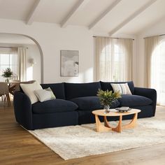 a living room filled with furniture next to a wooden table and white rug on top of a hard wood floor