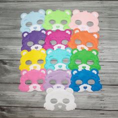 many different colored bear masks are arranged on a wooden surface with holes in the middle