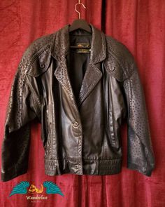 ✨ Materials & dimensions ✨ This is a vintage 1980s black leather motorcycle jacket, fully lined with perfect condition black satin. I could not find a size listed on it, but it fits a size 12-14, and would be a great oversized style for someone size 8-10. ✨ About this item ✨ This is a classic black leather 80s jacket with some unique touches. The jacket features a batwing style sleeve, carved buttons that have a wooden look to them, and a texturing on the sleeves and shoulders that gives a nod towards animal print. Made in the USA. Wear it with leggings and high tops with your door knocker earrings.  ✨ Gift giving ✨ This jacket will be presented wrapped in colorful paper, ready for gift giving or just for treating yourself. If this piece is a gift, it can be shipped directly to your recipi Vintage Black Leather Jacket For Winter, Vintage Black Leather Jacket For Spring, Vintage Black Retro Leather Jacket For Fall, New Wave Fashion, Black Leather Motorcycle Jacket, Moto Vintage, 80s Jacket, Satin Noir, Oversized Style