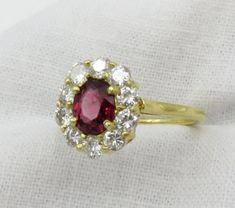 Sale.  Originally $2,975.00 A very pretty oval mixed cut Red Spinel surrounded by diamonds.  This spinel has a gorgeous red color and the diamonds surrounding the ring add a lovely sparkle and contrast.  A perfect non-traditional engagement ring. Overview: The ring is prong set with a oval mixed cut Red Spinel.  Prong set around the center stone are ten (10) round brilliant cut diamonds.  The top of the ring measures 12.0mm x 10.7mm x 6.1mm. The shank measures 1.40mm wide and 1.1mm thick. Size 6 Dazzling Oval Ruby Ring With Diamonds, Oval Rose Cut Diamond Ring With Ruby Accents, Dazzling Oval Ruby Ring, Dazzling Oval Ruby Ring With Halo Setting, Oval Ruby Halo Ring With Brilliant Cut, Red Diamond Cluster Ring With Halo Setting, Oval Ruby Cluster Ring With Rose Cut Diamonds, Oval Ruby Cluster Ring For Formal Occasions, Oval Ruby Ring With Rose Cut Diamonds