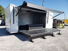 an enclosed trailer with the door open and some other vehicles in the back ground behind it