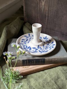 a stack of books sitting on top of a bed next to a cup and saucer