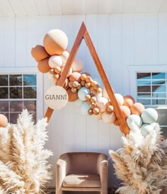 an arch made out of balloons and feathers is in front of a building with chairs