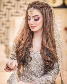 a woman with long hair wearing a bridal dress and holding a ring in her hand