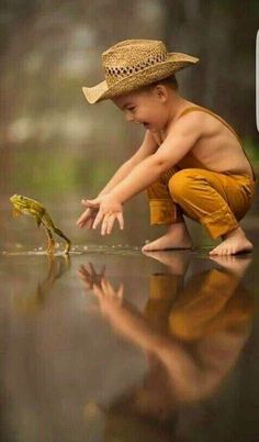 a little boy playing with a frog in the water