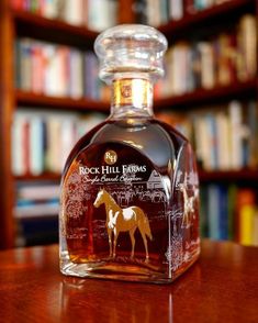 a glass bottle sitting on top of a table in front of a book shelf filled with books