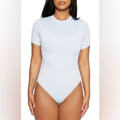 a woman in a white bodysuit with her hands on her hips