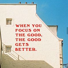 a white building with red lettering on the side and stairs leading up to it that says, when you focus on the good, the good gets better