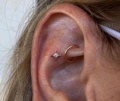 a woman's ear is shown with a tiny star and crescent piercing on it