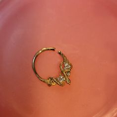 a close up of a gold ring on a pink plate with an animal motif in the middle