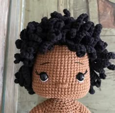 a crocheted doll with black hair and big eyes