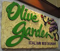 the sign for olive garden italian restaurant is green and has grapes on it's side