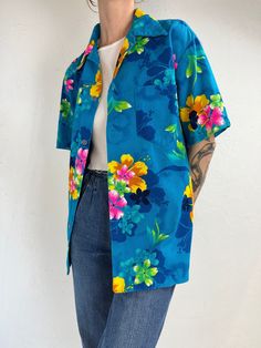 "- Vintage 1970s blue hawaiian print shirt - Feels like 100% polyester - Made in Hawaii - Tagged L Chest: 22.5\" Length: 26\"" Blue Hawaiian Shirt With Hibiscus Print For Summer, Blue Floral Print Hawaiian Shirt For Beach, Blue Hawaiian Shirt With Tropical Print, Blue Hawaiian Camp Shirt With Hibiscus Print, Blue Hawaiian Shirt With Floral Print, Blue Floral Print Hawaiian Shirt, Blue Button-up Hawaiian Shirt For Vacation, Blue Hawaiian Shirt With Floral Print And Camp Collar, Blue Floral Print Shirt For Vacation