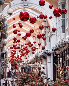 christmas decorations are hanging from the ceiling in an indoor shopping mall, decorated with red and white ornaments