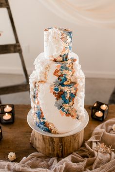 a three tiered cake sitting on top of a wooden table next to lit candles