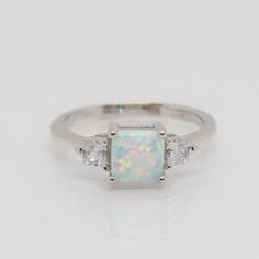 an opal and diamond ring with three stones on the side, set in white gold