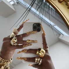 a woman holding up her cell phone with gold rings on the front and back of it