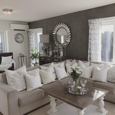 a living room filled with lots of furniture next to two large windows and a mirror on the wall