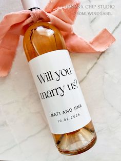 a bottle of wine sitting on top of a marble table next to a pink ribbon