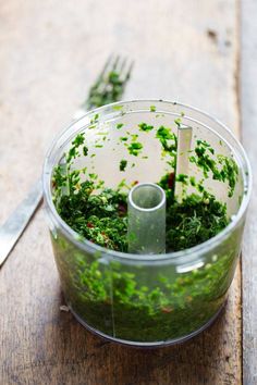 a food processor filled with green vegetables on top of a wooden table