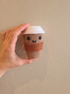 a hand holding a coffee cup made out of crochet