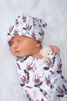 a newborn baby is wearing a white hat and holding a teddy bear in it's arms