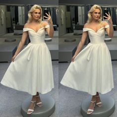 a woman in a white dress is standing on a pedestal and posing for the camera