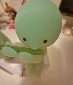 a small green toy sitting on top of a table next to a white countertop