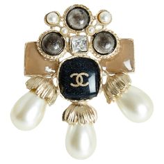 Chanel brooch AW2016 collection in lightly gilded metal (between gold and silver), XL format, central cabochon covered with slightly glittery black enamel and inlaid with a CC logo, cabochons of different shapes and slightly glittery colors, fancy pearls and white rhinestones. Width 5.9 cm x height 6.5 cm. The brooch is delivered without original invoice, in a pretty Chanel box, it is perfect with everything, every day... Chanel Ring, Chanel Brooch, Chanel Box, Chanel Accessories, White Rhinestone, Cc Logo, Black Enamel, Gold And Silver, Karl Lagerfeld