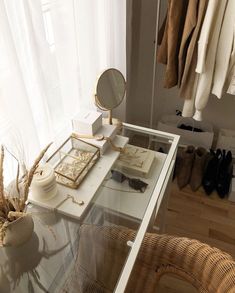 a white desk topped with a mirror next to a wicker chair and coat rack