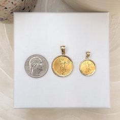 three gold and silver coin pendants sitting on top of a white cloth covered box