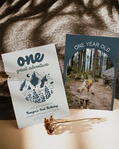 one year old greeting card and book laying on a bed in the woods with an image of a young boy