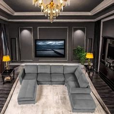 a modern living room with gray couches and chandelier above the tv on the wall