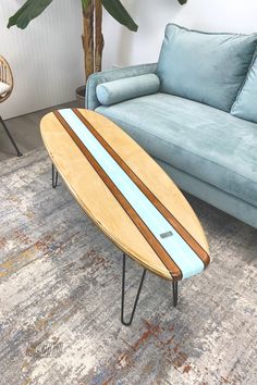 a surfboard sitting on top of a metal stand in front of a blue couch