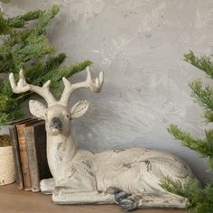 a white deer statue sitting on top of a wooden table next to a potted plant