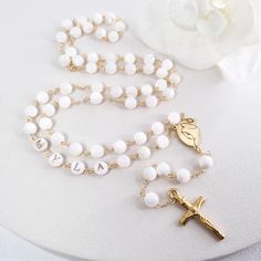 This Personalized Rosary, is ideal as a Baptism gift for a little girl or baby boy or as a gift for a special occasion. It is expertly handcrafted in a traditional style with a contemporary twist utilizing genuine Mother of pearl stone and gold-plated brass wire, which not only gives a touch of nature but also tenderness. The letter beads on the Rosary are also handmade from genuine mother of pearl, and the length is perfect to worn as a dainty Rosary necklace for women. *MATCHING ROSARY BRACELE White 8mm Beads Jewelry As Gift, White Jewelry With 8mm Beads For Gift, White Jewelry With 8mm Beads As Gift, Beaded Cross Jewelry For First Communion, Cross-shaped Beaded Jewelry For First Communion, Personalized Cross Rosary Bracelet For Baptism, Handmade White Rosary Bracelet For Wedding, Pearl White Rosary With 8mm Beads As Gift, Personalized Spiritual Rosary Bracelet