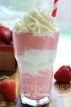 a strawberry milkshake with whipped cream and strawberries in the background on a wooden table