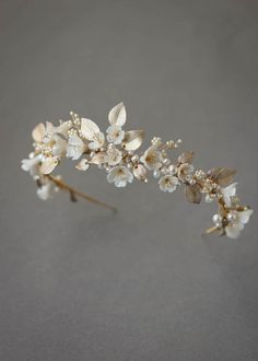 a close up of a flower headpiece on a gray surface with white flowers and leaves