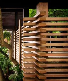 a wooden fence in front of a tree and some bushes on the side of a building