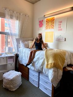 a woman sitting on top of a bed in a bedroom next to a large window