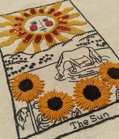 the sun embroidered onto a white shirt with yellow and black flowers in front of it