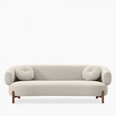 a white couch with two pillows on top of it's back legs and arms